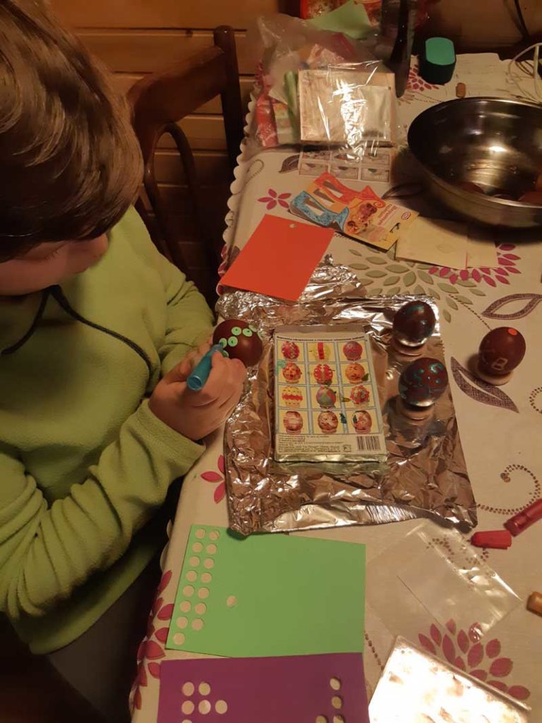 Olga's son enjoys the craft of decorating eggs at the dacha.