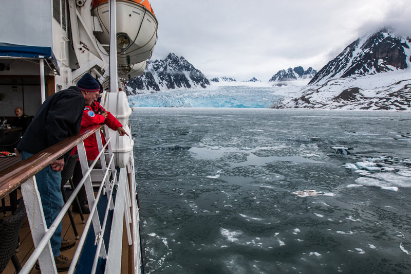 Spotting sea life from the deck, with a blue glacier backdrop. Photo credit: Jonathan Zaccaria