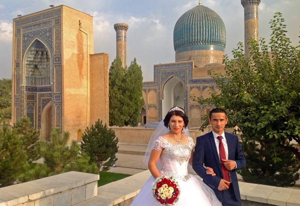 Newlyweds pause for pictures among Samarkand’s ancient architecture. Photo credit: Michel Behar