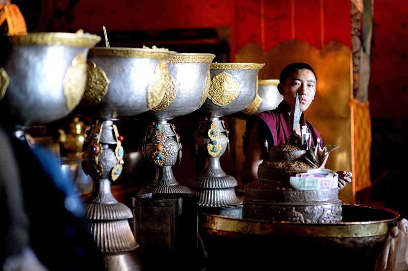 Tibetan monk with ritual cups. Photo credit: Phil Kidd