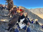 Eagle hunters and their birds perched on a mountain.