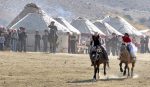 Horses race in front of yurts.