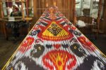 Close-up of a traditional handwoven textile with colorful patterns stretched out on a wooden loom.