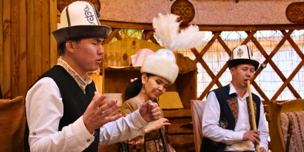Kyrgyz performers inside a traditional yurt, wearing national attire including kalpak hats | MIR Corporation